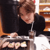 a man is sitting at a table with a grill and a glass of soda