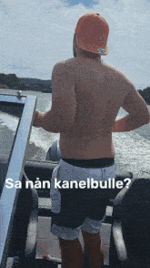 a shirtless man standing on a boat with the words sa nan kanelbulle on the bottom