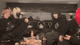 a group of people are sitting on a couch and one of them is wearing a black shirt with the letter p on it