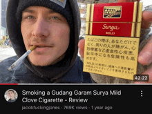 a man smoking a gudang garam surya mild clove cigarette is shown