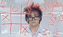 a man with glasses is standing in front of a tic tac toe board .