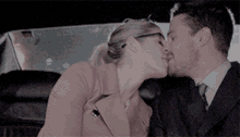 a man and a woman are kissing in the back of a car