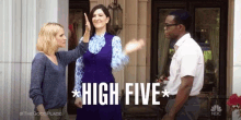 a woman is giving a high five to another woman while standing next to a man .