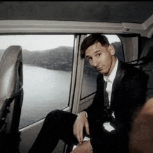 a man in a suit is sitting in the back seat of a car next to a window .