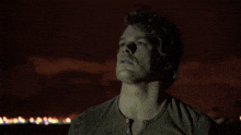 a man in a brown shirt looks up into the night sky