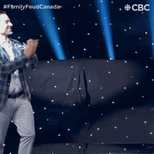 a man in a plaid jacket is dancing on a stage with a cbs logo