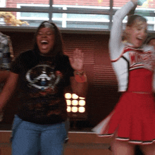 a cheerleader wearing a red and white uniform with the word glee on it stands next to another cheerleader