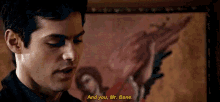 a man is talking to another man in front of a painting and says `` and you , mr. bane '' .