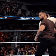 two men are in a wrestling ring with a sign that says smack
