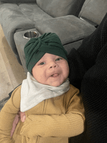 a baby wearing a green turban and a white bib
