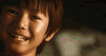 a close up of a young boy 's face smiling in the dark