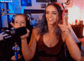 a woman wearing headphones stands in front of a shure microphone while another woman looks on