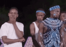 a group of men are standing next to each other with one wearing a blue headband with the letter t on it .