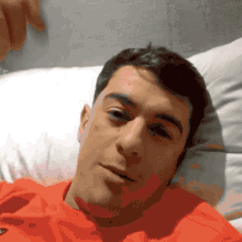 a man in a red shirt is laying down on a bed