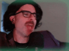 a man wearing glasses and a fake mustache is talking into a microphone .