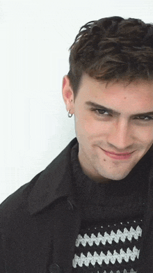 a young man wearing a black jacket and a black and white sweater