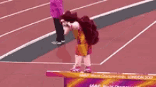 a mascot is standing on a hurdle on a track .