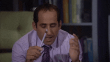 a man in a striped shirt and tie holds a pen to his mouth