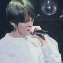 a man singing into a microphone with green hair