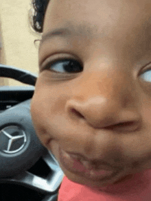 a baby is making a funny face in front of a mercedes logo