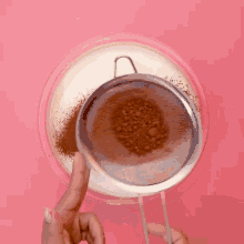 a person is sifting cocoa powder into a glass bowl