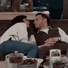 a man and a woman are sitting on a couch kissing each other .