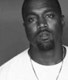 a man with a beard is wearing a white shirt and a necklace .