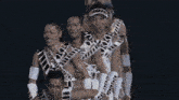 a group of men are standing in a line and one of them is wearing a hat that says ' x ' on it
