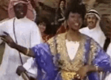 a woman in a blue and gold dress is dancing in front of a crowd of people .