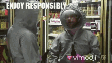 a man in a hazmat suit is standing next to another man in a fridge with the caption enjoy responsibly