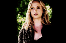a woman with blonde hair and a black shirt is standing with her arms crossed .