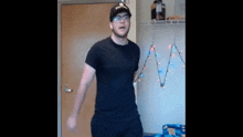 a man wearing a hat and glasses is standing in a room .
