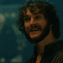 a man with curly hair and a beard smiling