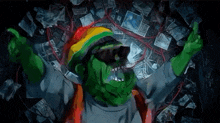 a green monster wearing a rasta hat and sunglasses is giving a middle finger .