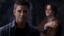 two men are standing next to each other in a dark room and smiling at each other .