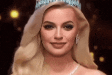 a woman wearing a tiara and pearls smiles for the camera