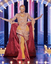 a woman in a long red dress is standing on a stage