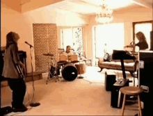 a group of people are playing instruments in a living room while a woman sings into a microphone .