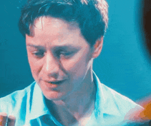 a man in a blue shirt looks down at something