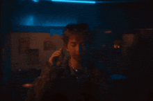 a man holding a piece of paper in front of his face in a dark room