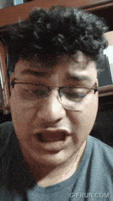 a man wearing glasses making a funny face with gifrun.com in the corner