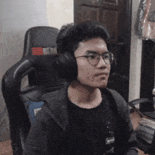 a man wearing headphones and glasses is sitting in a chair that says red label on it