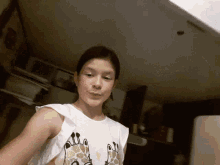 a girl wearing a giraffe t-shirt is standing in a kitchen