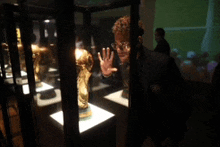 a man in glasses looks at a trophy in a glass case