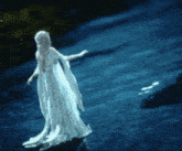 a woman in a long white dress is standing on a rock