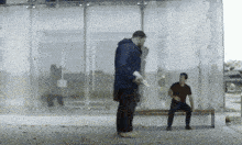 two men are standing next to each other on a sidewalk in front of a building .