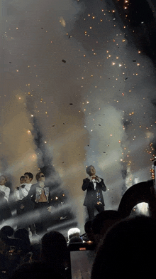 a group of people standing on a stage with confetti falling