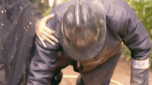a fireman wearing a helmet is being helped by another fireman