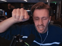 a man wearing ear buds and a blue and white striped shirt is making a fist
