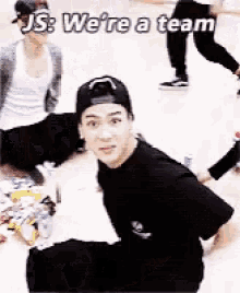 a group of people are sitting on the floor and one of them says " js we 're a team "